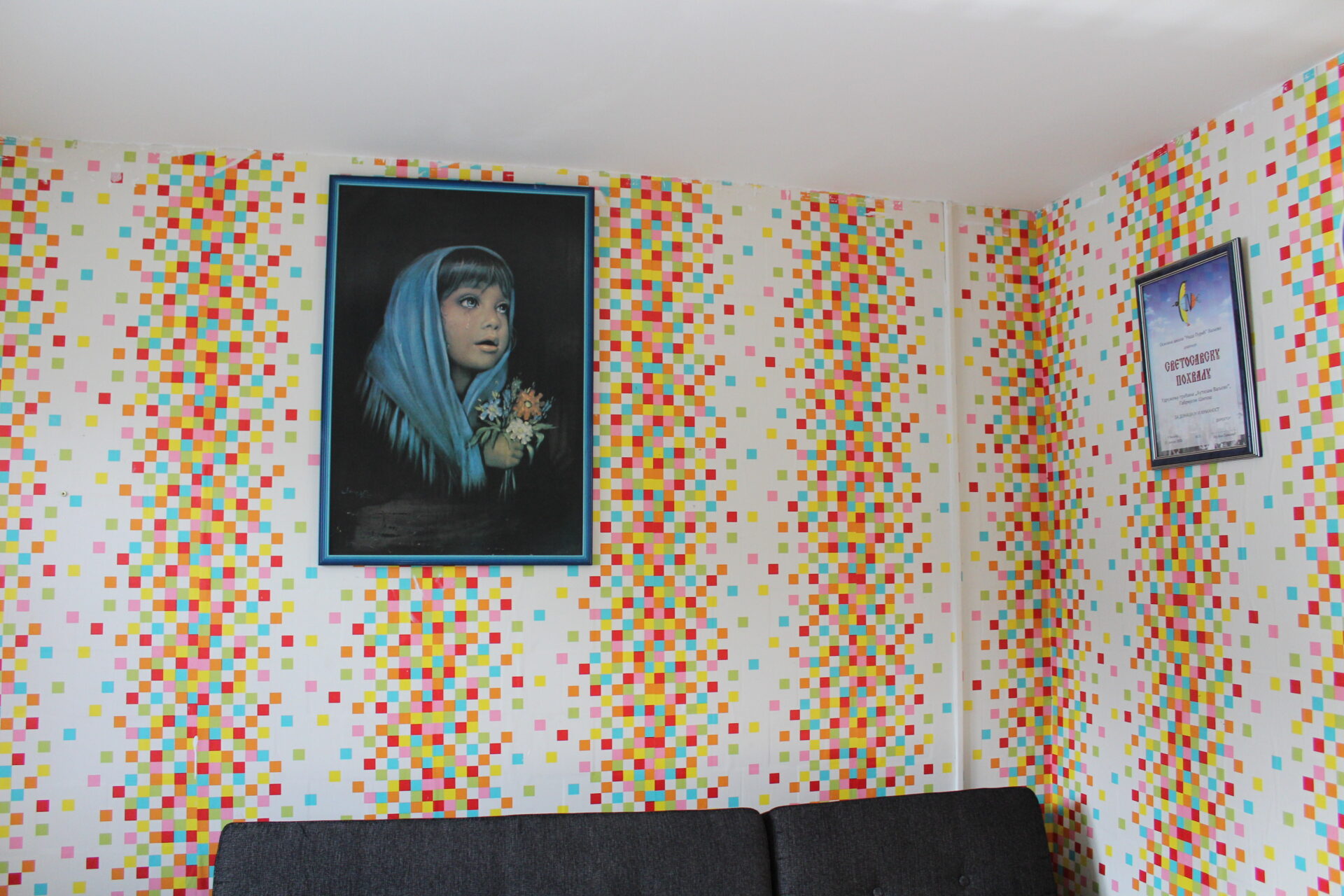 A view of a framed artwork mounted on a colorful wall above a gray couch
