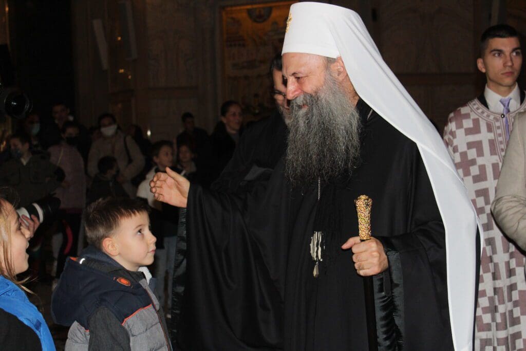 Bearded man in white headcover greeting children