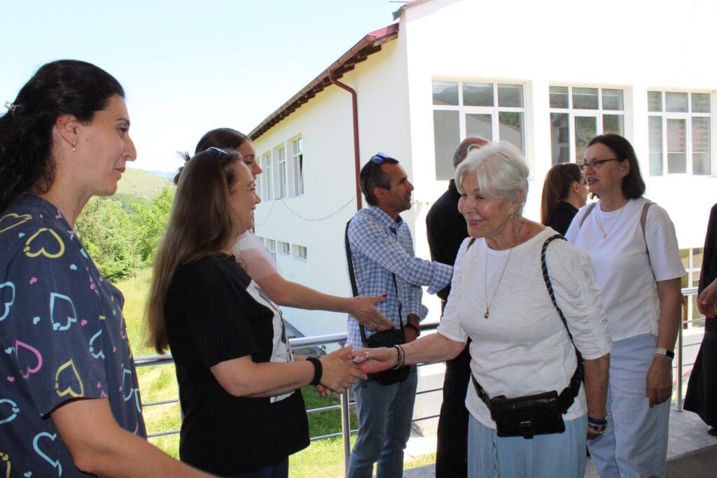 Elderly woman shaking hands with group