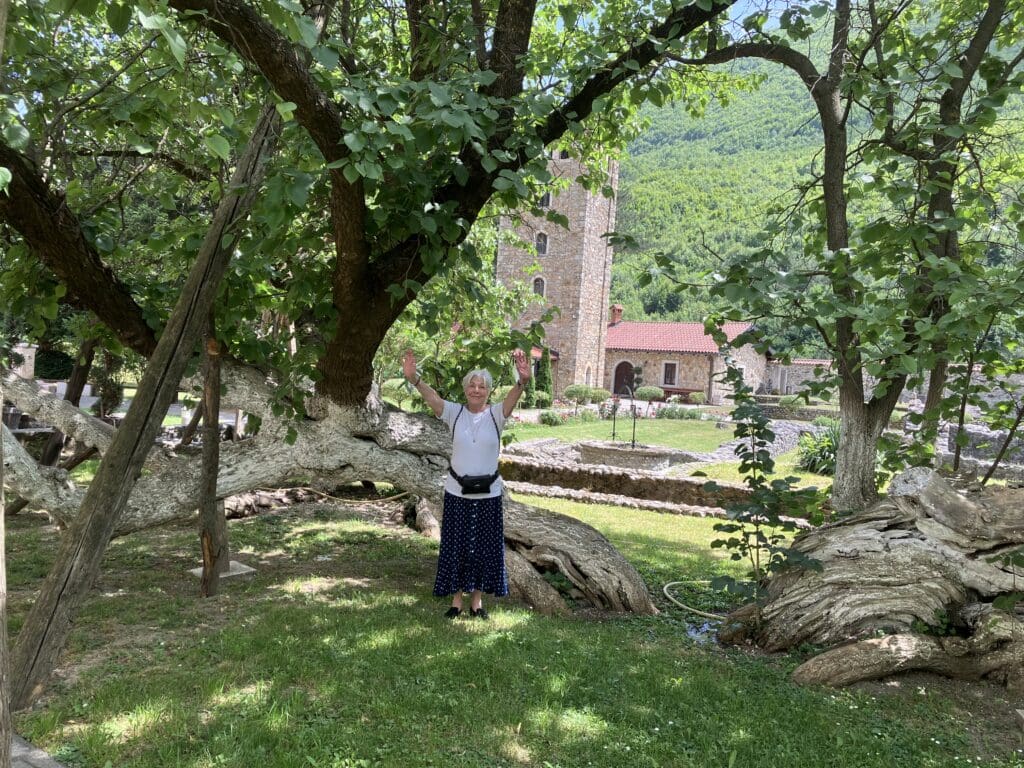 Woman raising arms under ancient sprawling tree