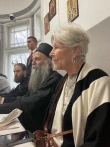 Elderly woman and bearded men seated at table