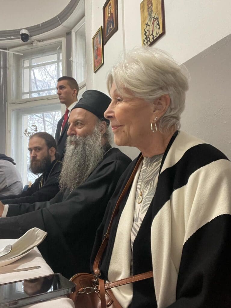 Elderly woman and bearded men seated at table