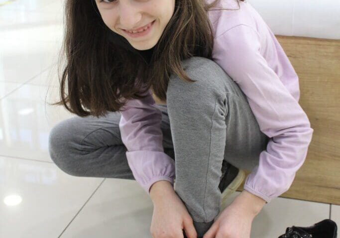 Smiling girl trying on sneakers in shoe store