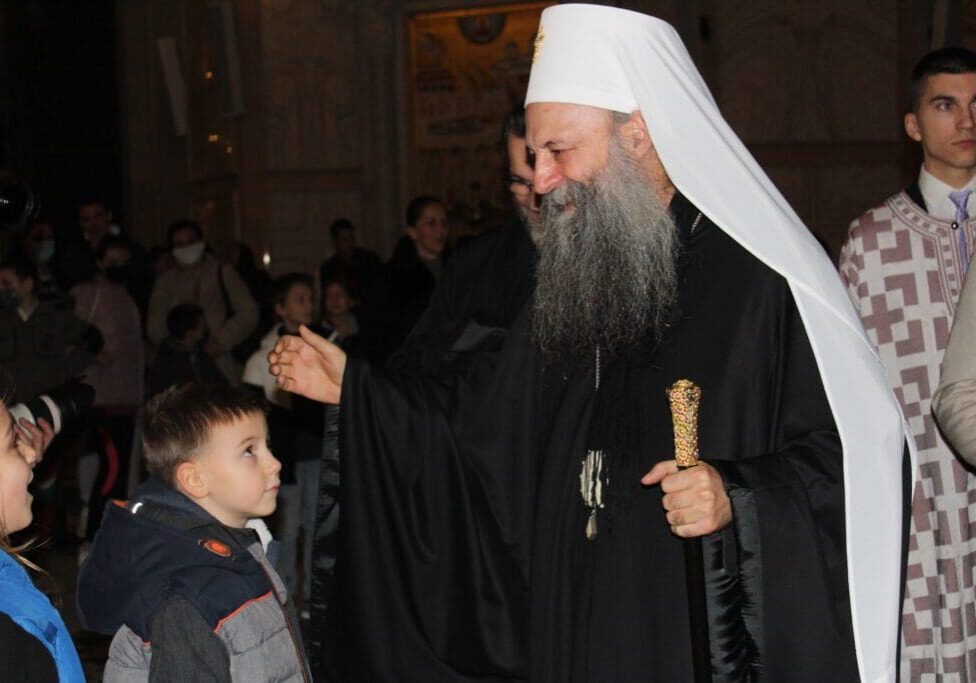 Bearded man in white headcover greeting children