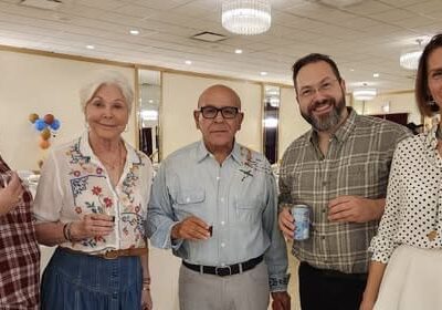 Five people smiling at a casual gathering.