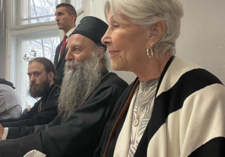 Elderly woman and bearded men seated at table