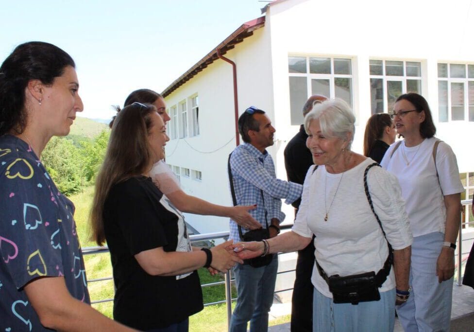 Elderly woman shaking hands with group